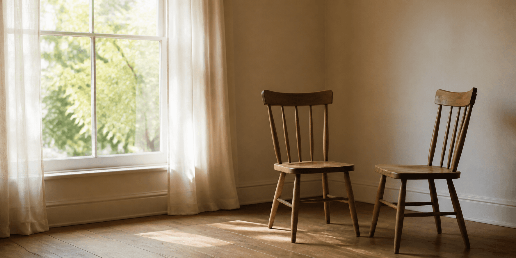 Two simple wooden chairs beside a window in quiet morning light
